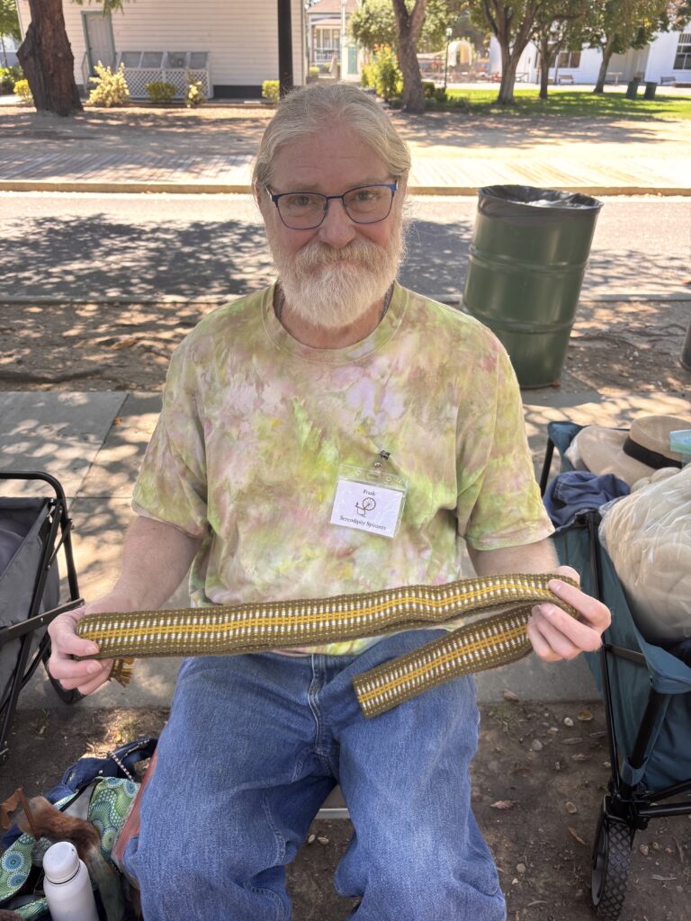 Frank holding up his strap woven on an inkle loom