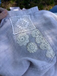 visible mending on a shirt using old lace pieces to create patches